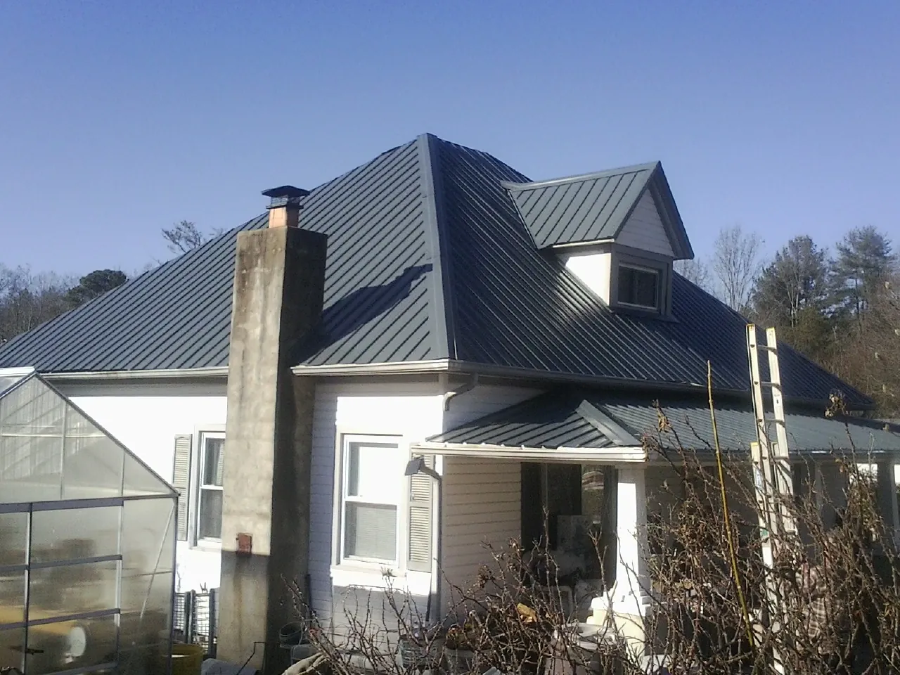 Dark blue standing seam metal roof on a white farmhouse with dormer — Slate & Tile Roof Repair by Roofing Brothers in Rosebud