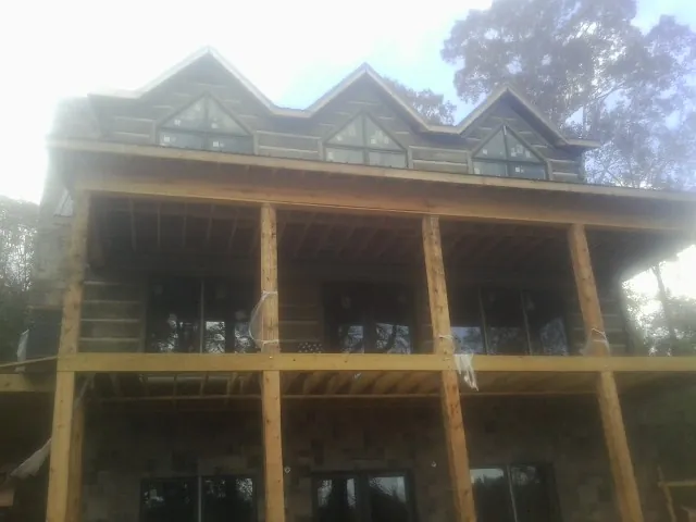 Dormers and porch framing on a large log home under construction — Roof Coating work by our crew in Rosebud